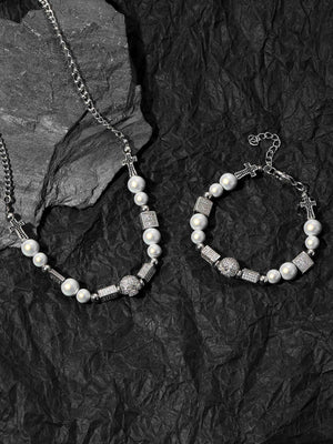 Pulsera de cuentas con cruz de perlas y calavera de strass – junto al collar sobre roca negra | XoKool