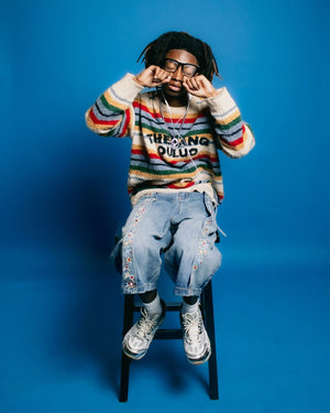 Fuzzy striped sweater – on model, seated studio | XoKool