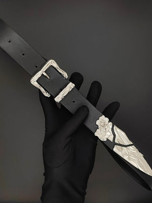 Schwarzer Gürtel mit graviertem silberfarbenem Schnallen- und Spitzenbeschlag – in der behandschuhten Hand, Schnalle und Spitze | XoKool