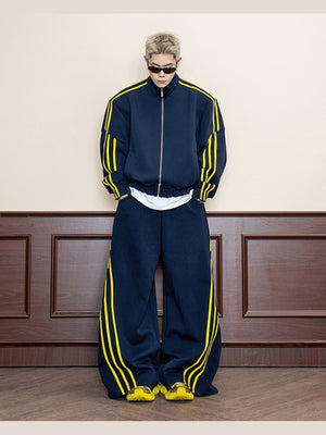 Pantalones deportivos de pierna ancha azul marino con rayas amarillas – en modelo, frente, con chaqueta deportiva a juego | XoKool