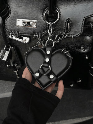 Taschenanhänger in Herzform mit Nieten und Harness-Band – schwarzer Anhänger an Tasche, in der Hand | XoKool