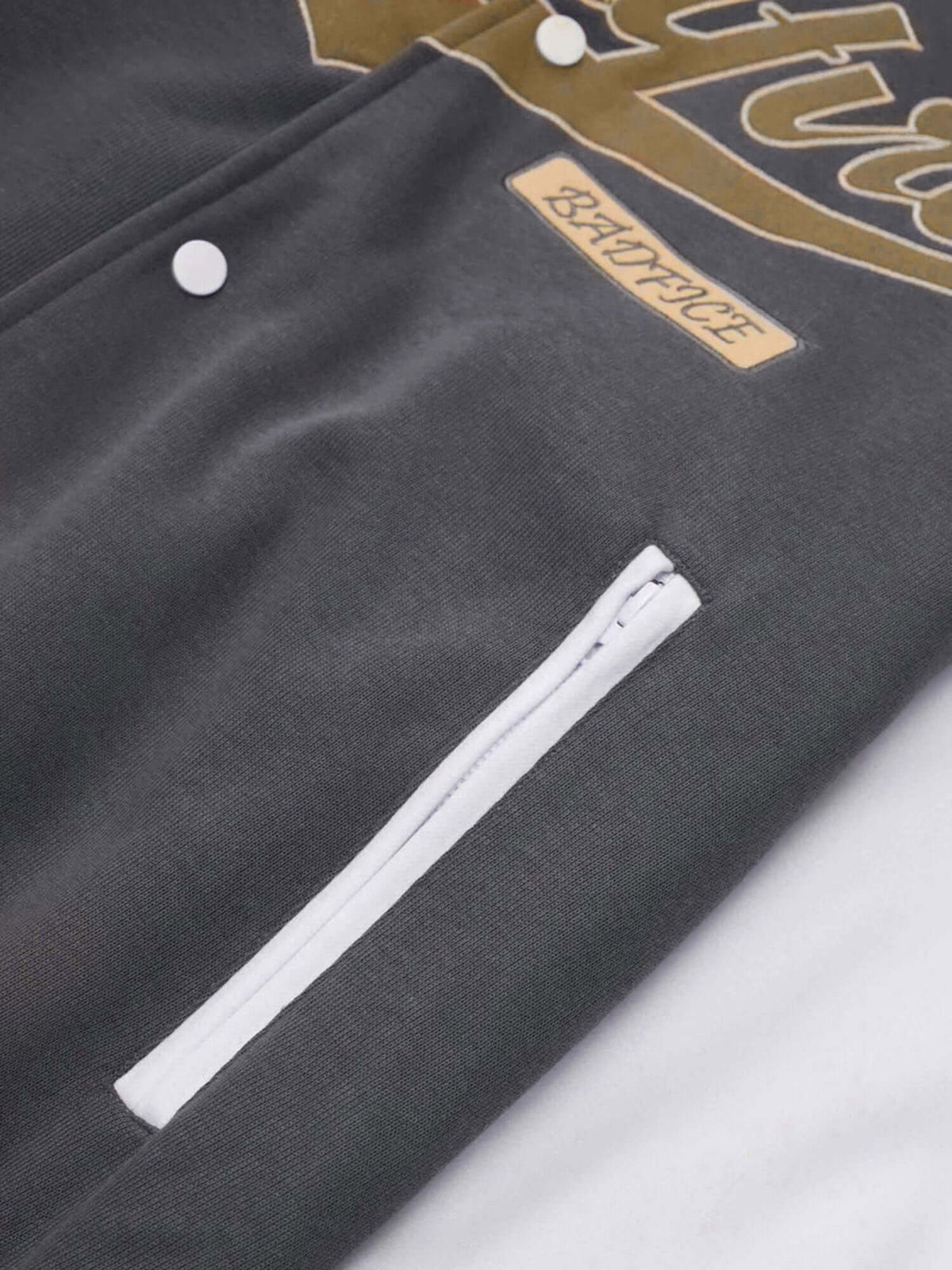 Graue Varsity Jacke – seitliche Reißverschlusstasche und Patch im Detail | XoKool