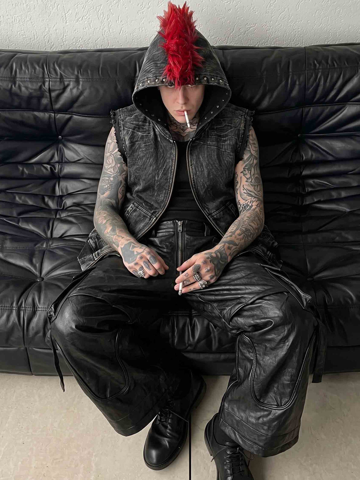Chaleco de denim negro con capucha y escudo de piel sintética roja – en modelo, sentado | XoKool