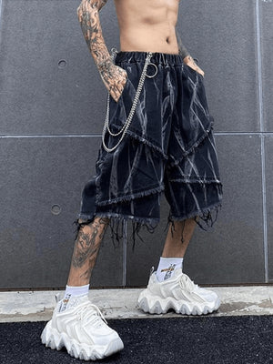 Shorts de denim negros en capas con estampado de trazos abstractos – en modelo, vista frontal con cadena | XoKool