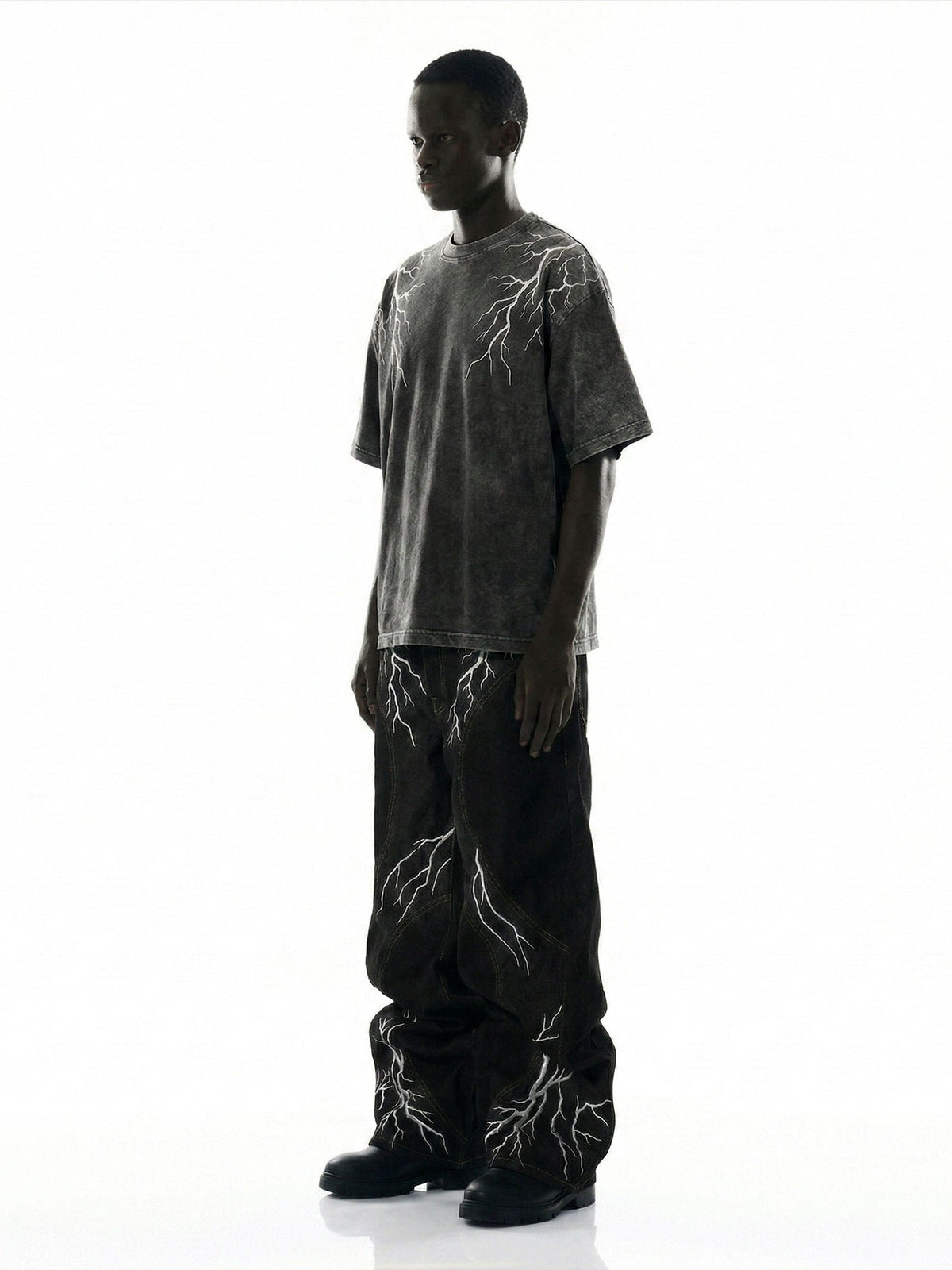 Schwarze Stacked Jeans mit Blitz-Graphics – am Model, Seitenansicht | XoKool