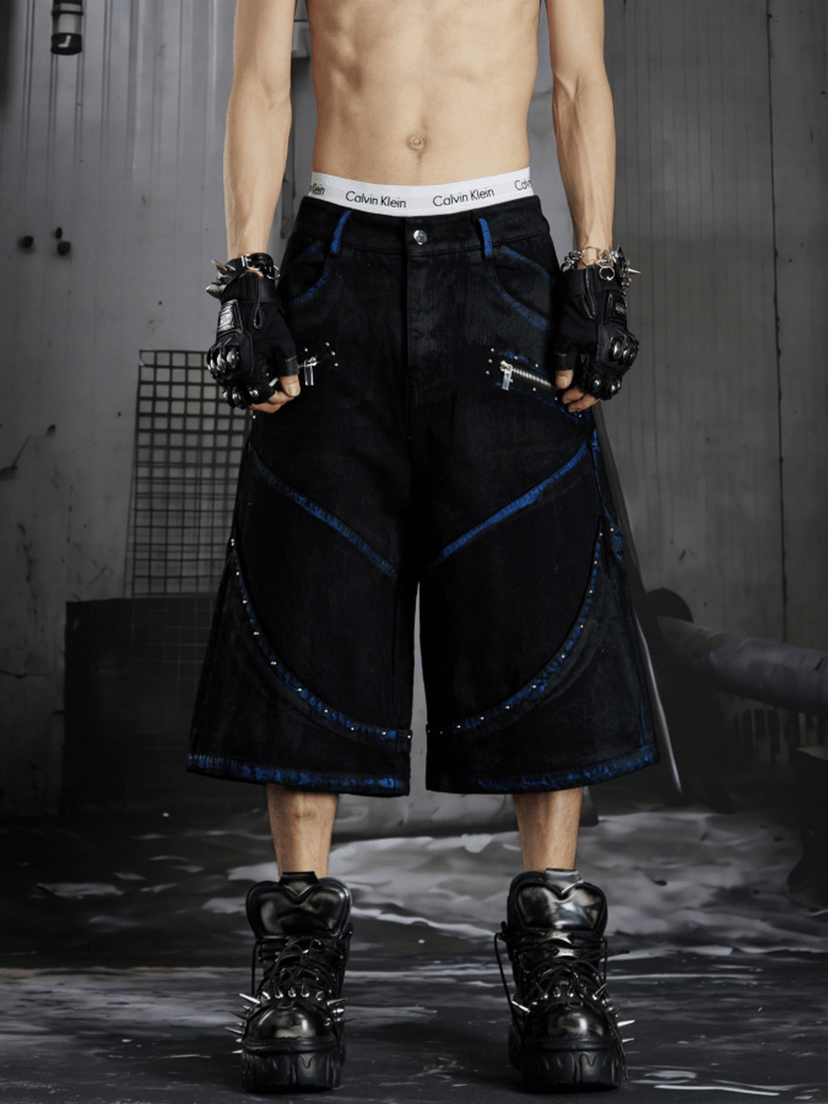Schwarze Jorts mit Nieten, blauen Details und Reißverschlusstaschen – am Model von vorne | XoKool