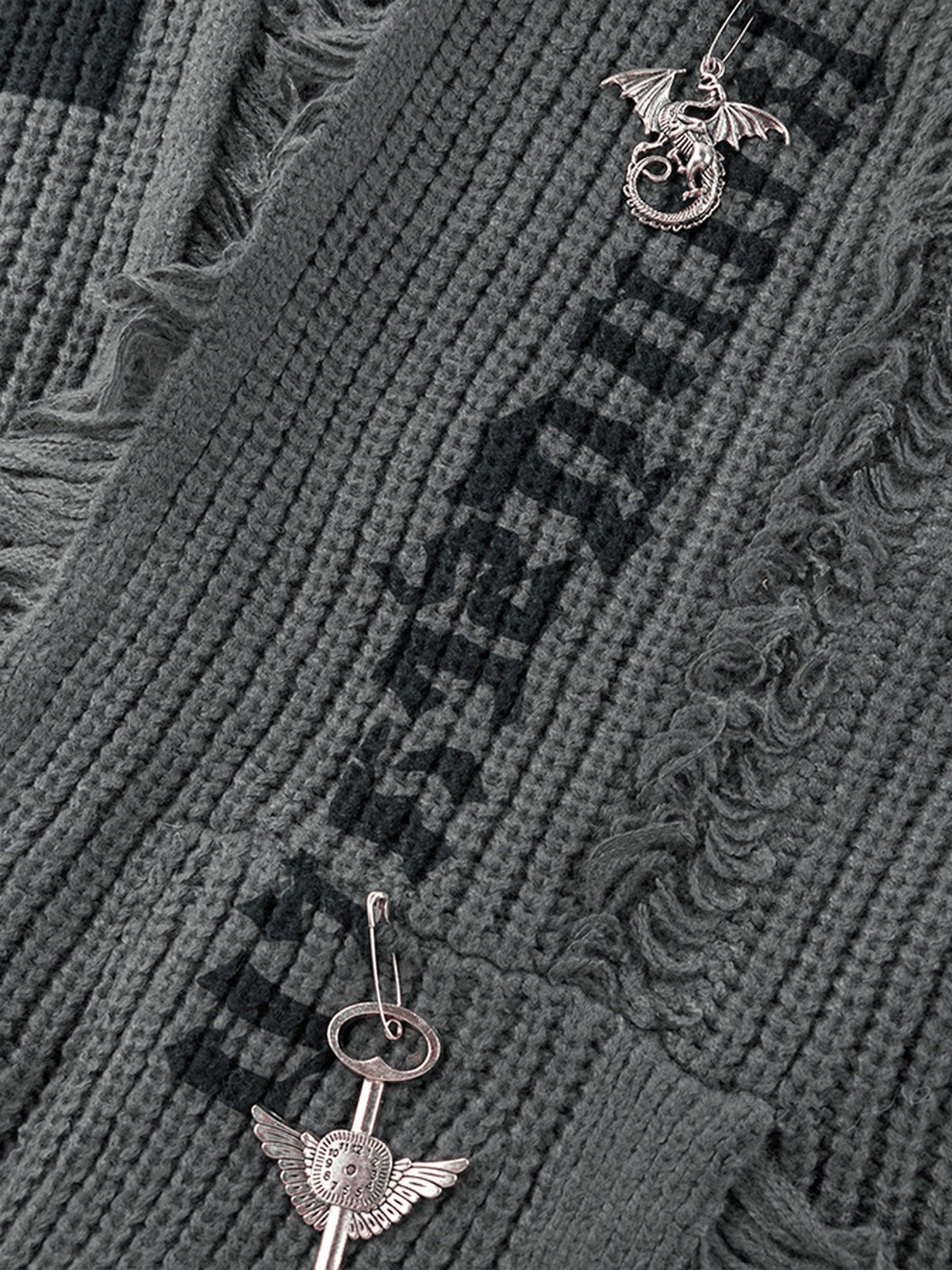 Strickjacke aus Grobstrick mit offener Front – Nahaufnahme Drachenanhänger und gotische Schrift | XoKool