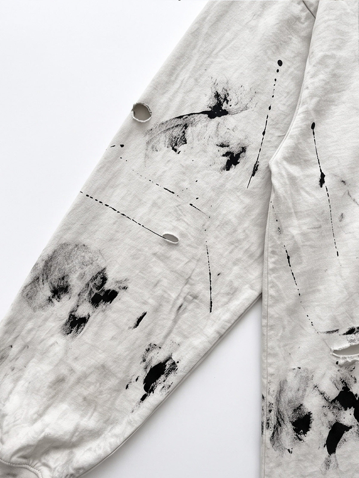 Camiseta de manga larga desgastada con salpicaduras de pintura y cruz estampada – primer plano de la manga con agujeros y salpicaduras | XoKool