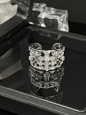 Anillo con banda de cruz calada y piedras transparentes – anillo sobre bandeja de espejo, vista frontal | XoKool