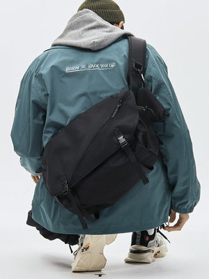Techwear Messenger Crossbody Bag with Buckle Flap – on model, worn on back over teal jacket | XoKool