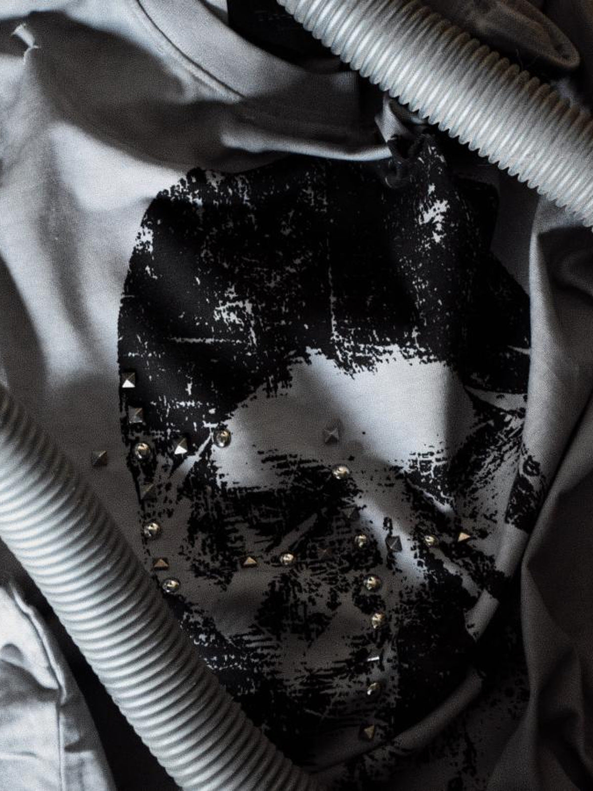 Camiseta sin mangas gris lavado con tachuelas y estampado de cara – primer plano del estampado y las tachuelas | XoKool